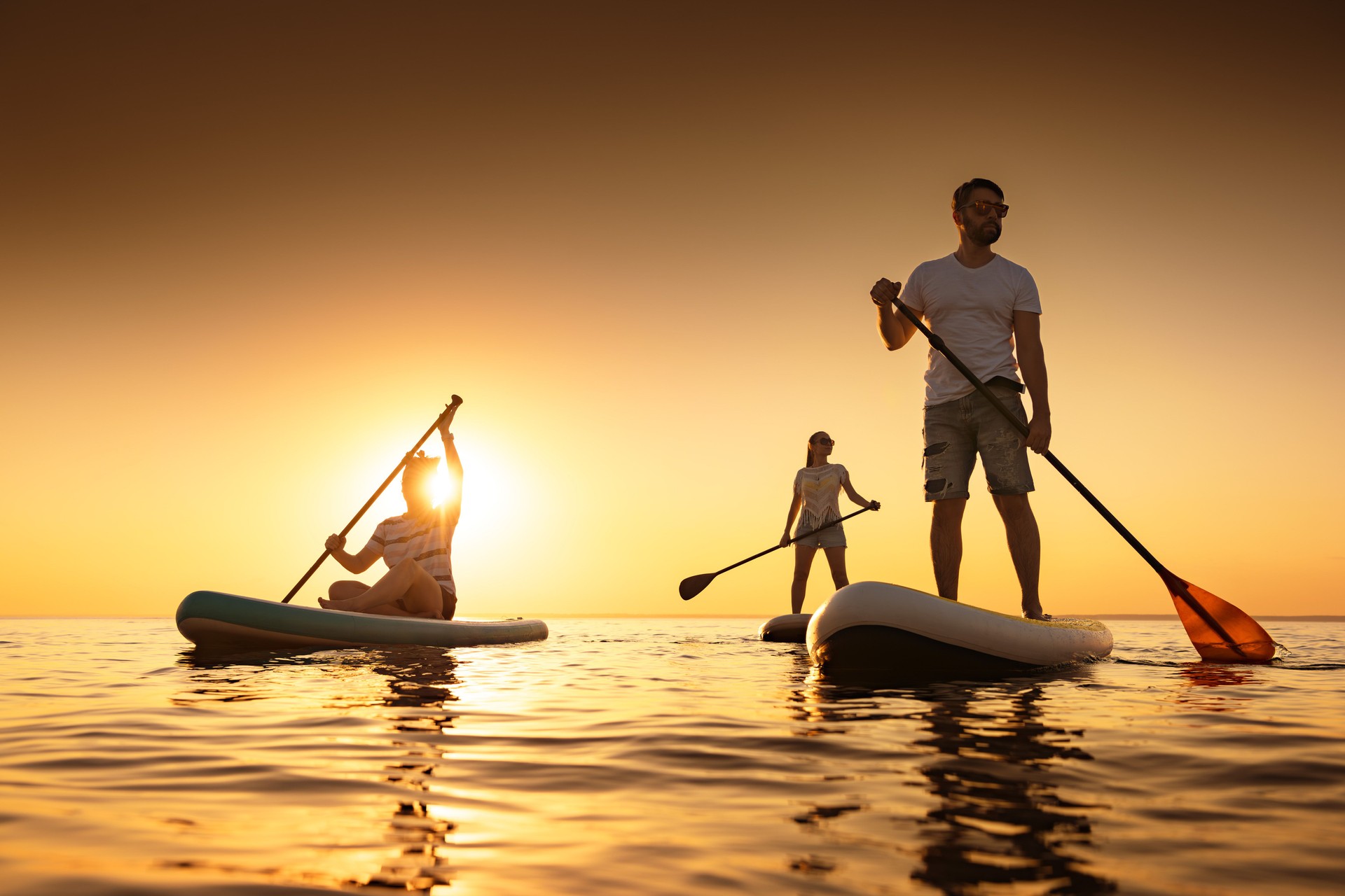 Group of silhouettes on paddle boards at sunset calm lake
